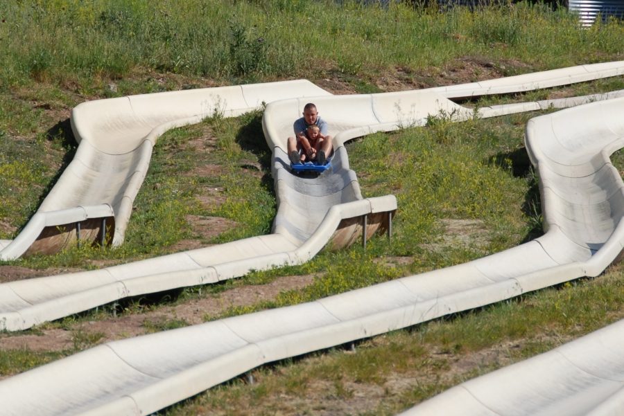 A rider on a blue sled descending a zigzagging pair of alpine slide tracks